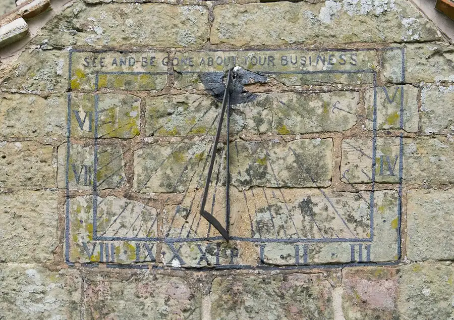 A weathered stone sundial with Roman numerals and an iron gnomon